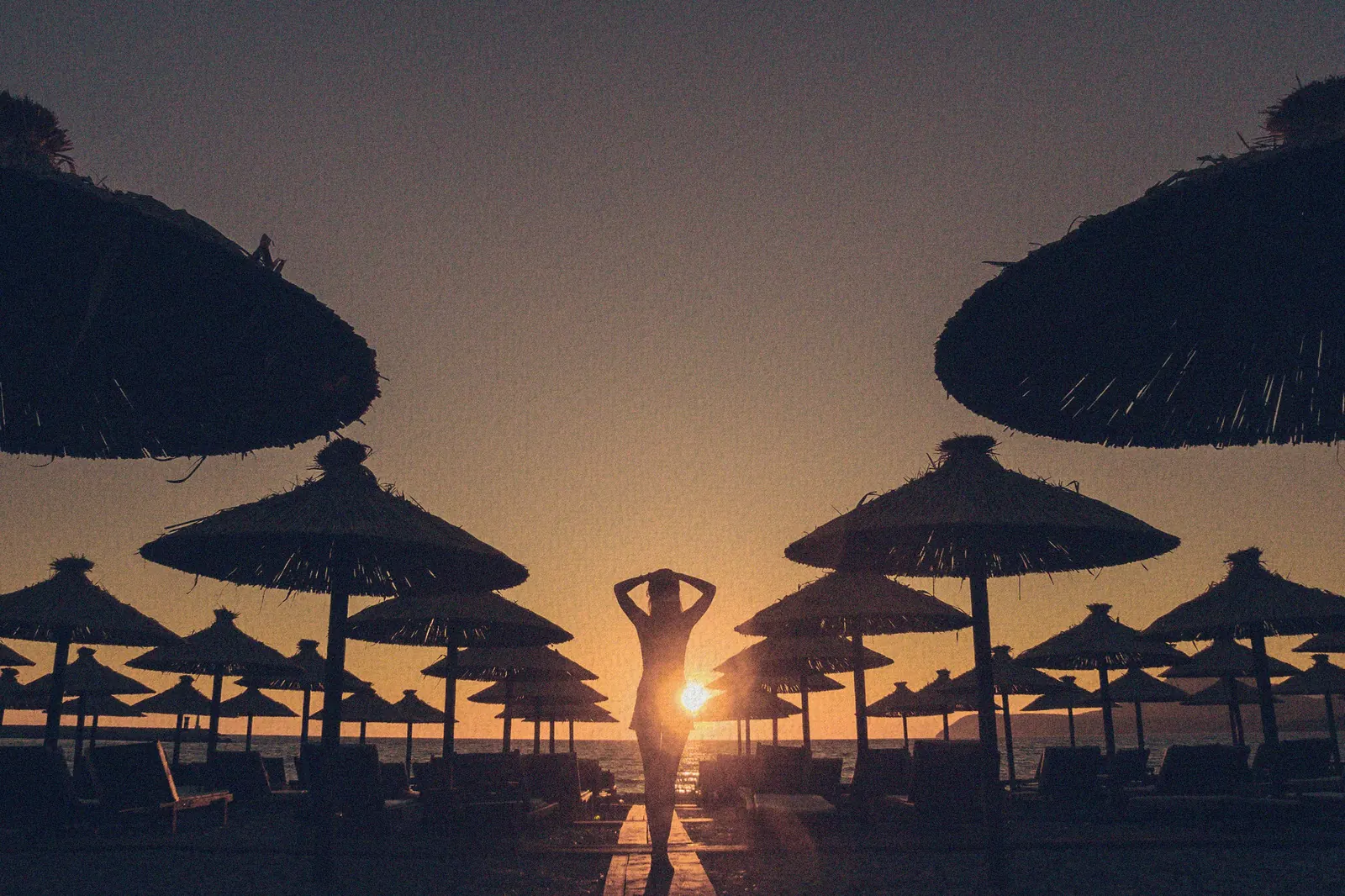 Siluetas de palapas en la playa al atardecer