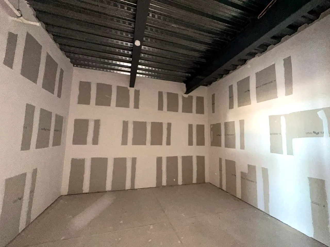Interior de la oficina en obra gris, con techo de losacero aparente
