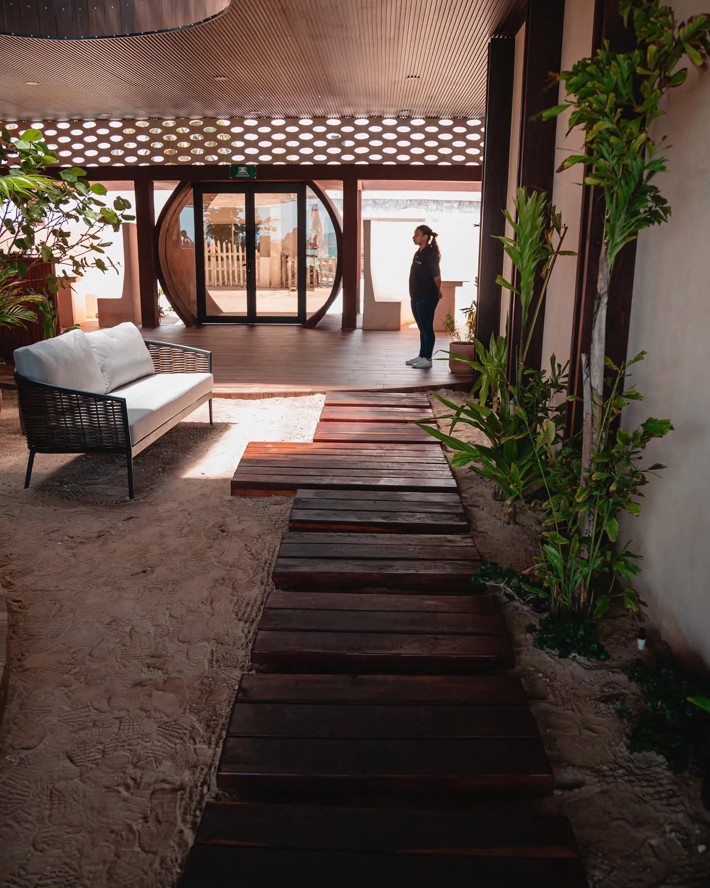 Zona lounge de Playaviva con sillón sobre la arena y pasillo de madera
